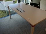 une table blanche sur laquelle est posé un téléphone portable, devant une fenêtre