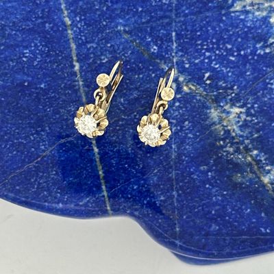 pair of diamond earrings on a blue stone slab