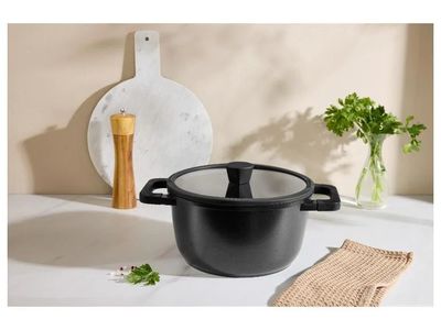 La casserole noire est posée sur le plan de travail, à côté d'une planche à découper.