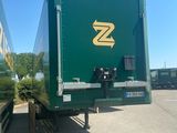 a green semi trailer parked in a parking lot