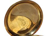 a gold pocket watch sitting on top of a white surface