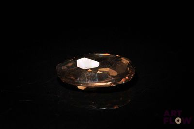 un gros plan d'un diamant à facettes sur une surface noire