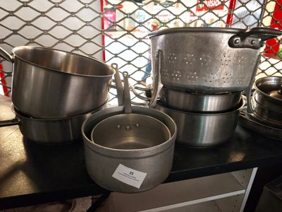 Plusieurs casseroles et poêles sont posées sur le plan de travail de la cuisine.
