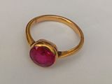 a close up of a gold ring with a pink stone