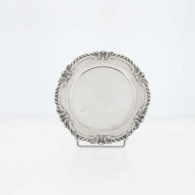 an antique silver plate on a stand on a white surface