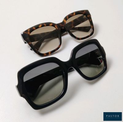 two pairs of sunglasses sitting on top of a white table