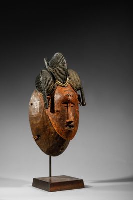 un gros plan d'une sculpture en bois représentant un visage, posée sur un socle