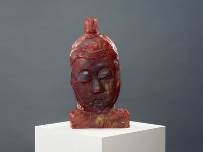 sculpture of a woman ' s head on a white pedestal against a gray background