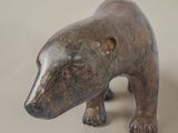 a small bronze bear that is standing on a white surface