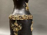 a black vase with gold decorations on it on a stand