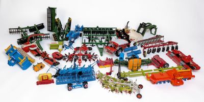 de nombreux tracteurs miniatures et du matériel agricole posés sur une surface blanche