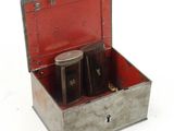 a metal box with two jars in it on a white surface