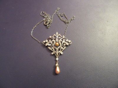 un collier en argent avec un pendentif en perle et une chaîne, posé sur une table