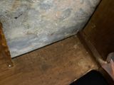 a toilet in a dirty bathroom with a wooden floor