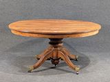 une petite table ronde avec un plateau en bois, montée sur roulettes
