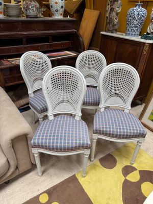 four white cane back chairs with blue and white checkered upholstered upholstered cushions