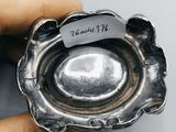someone is holding a silver ashtray with a note on it
