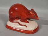 figurine of a brown rat on a white base on a gray background