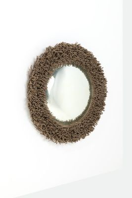 un miroir rond accroché à un mur blanc, avec un cadre marron