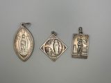 three silver pendants of the virgin mary and jesus