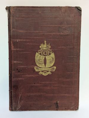 un vieux livre brun portant un emblème doré