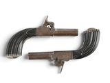 two old guns are on display on a white surface