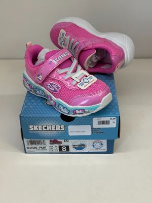 des chaussures Skechers roses à semelles blanches posées sur une boîte bleue