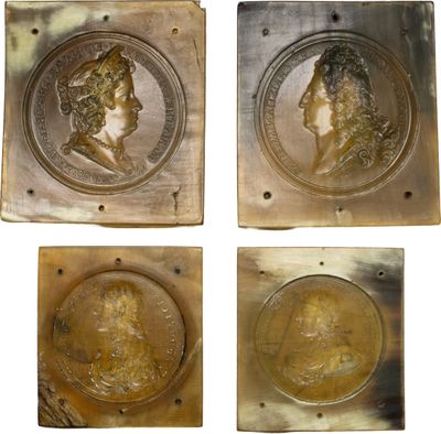 un ensemble de quatre plaques en bronze représentant la tête d'un homme et d'une femme