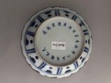 a blue and white plate on the wall with a tag on it