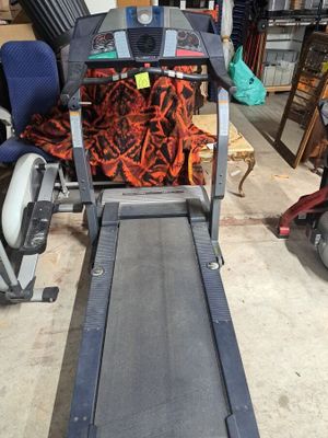 un gros plan sur un tapis de course dans un garage, avec une chaise en arrière-plan