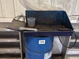 a blue barrel sitting next to a metal table