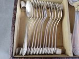 a lot of silver spoons and forks in a box