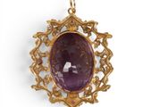 a close up of a pendant with a purple stone in it