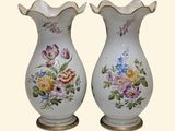 two vases with flowers painted on them sitting on a table