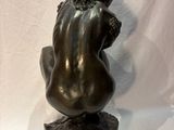 bronze sculpture of a woman sitting on a rock