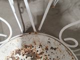 rusted metal table and chairs in a room with concrete flooring