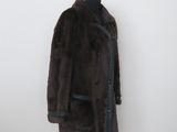 brown fur coat on a mannequin stand in front of a white wall