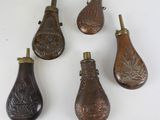 six petites cuillères en bois sont alignées sur une surface blanche