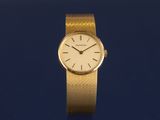 a close up of a gold wrist watch on a blue surface