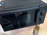un micro-ondes noir posé sur un carton posé à même le sol