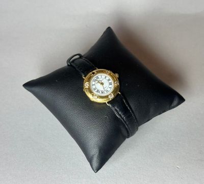 un petit oreiller noir sur lequel repose une montre en or