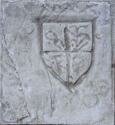 une plaque en pierre sur laquelle figurent des armoiries et une croix