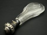 une cuillère en verre avec un manche en argent posée sur une surface noire