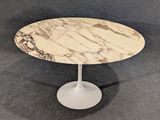 une table ovale en marbre avec un piètement blanc et un socle blanc