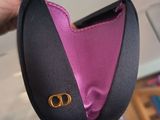 a hand holding a black and pink purse with a gold buckle