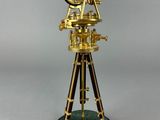 a gold plated telescope on a wooden stand with a green marble base