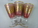 three wine glasses with gold designs on them sitting on a table