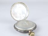 a silver pocket watch sitting on top of a white table
