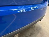 a close up of a blue car parked in a parking lot