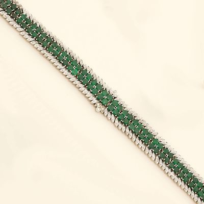 a close up of a green and white bracelet on a white surface